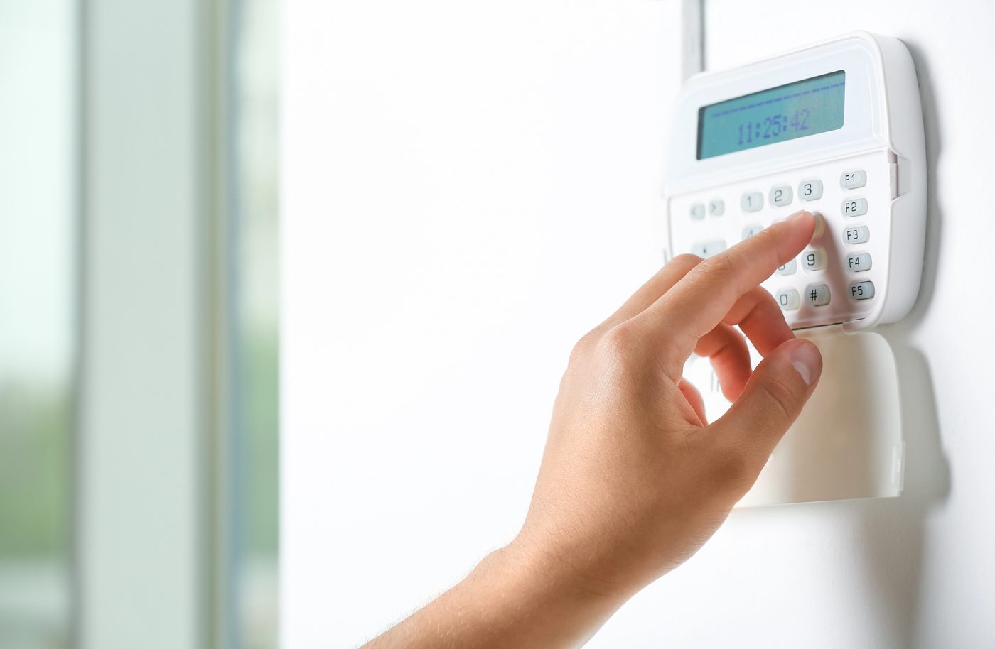 Hand entering code into home security monitoring system in a Lake Elsinore home.